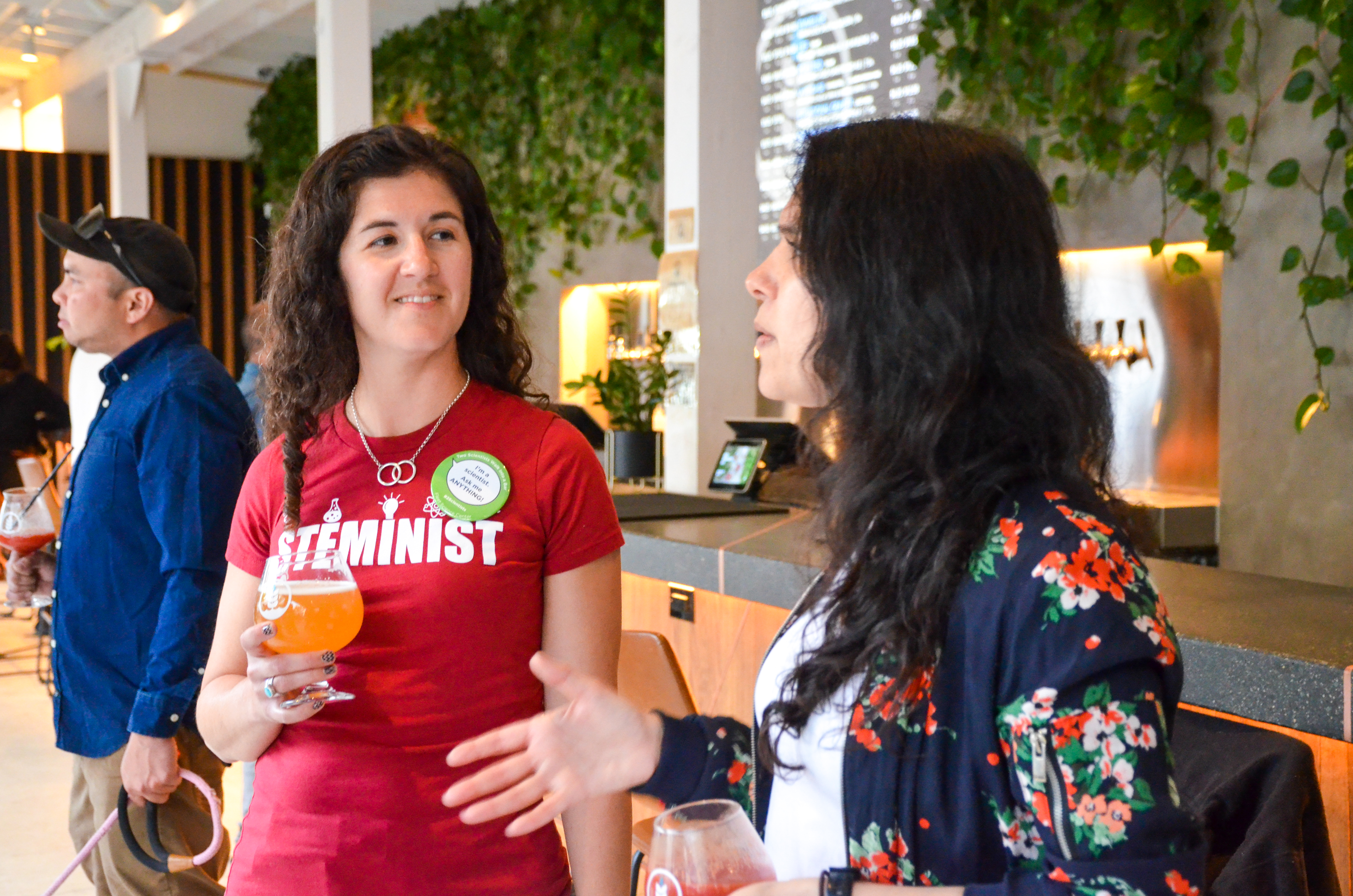 Two STEM professionals conversing at a bar, drinks in hand, enjoying a friendly and vibrant exchange.