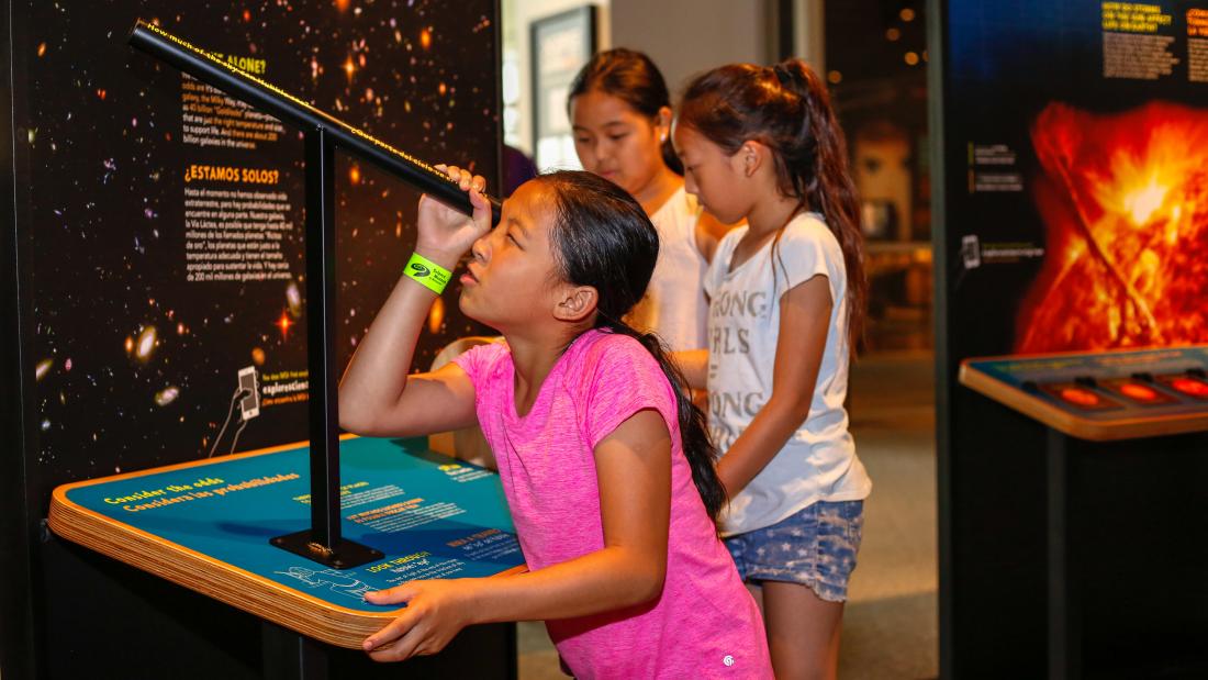 Girl looking through telescope at the Sun, Earth, Universe experience