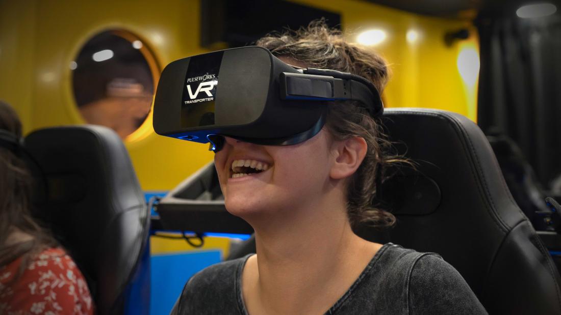 Young woman wearing a VR headset smiling and laughing at the Fleet Science Center