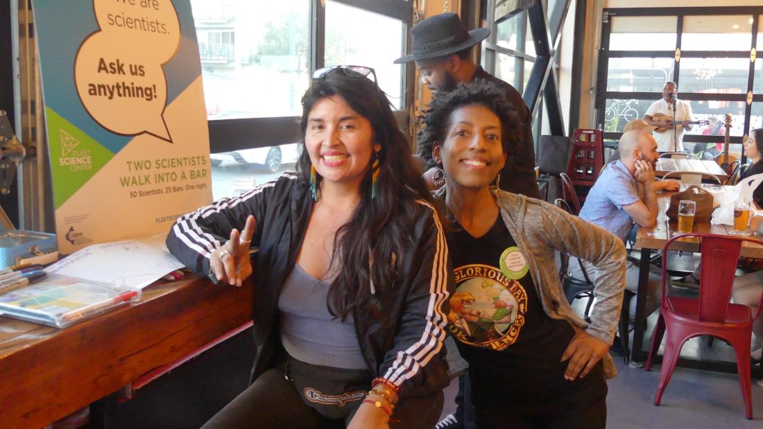 Two women pose in a brewery and smile