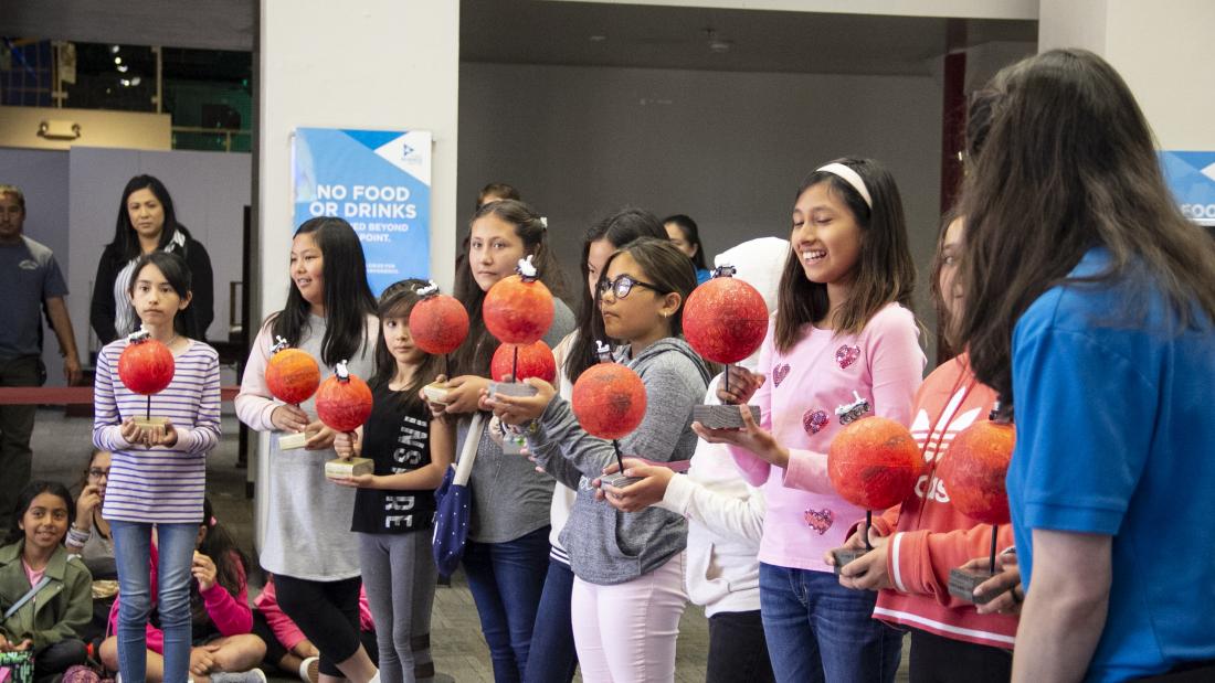 SciTech students smiling and presenting models of Mars with a rover on their models.