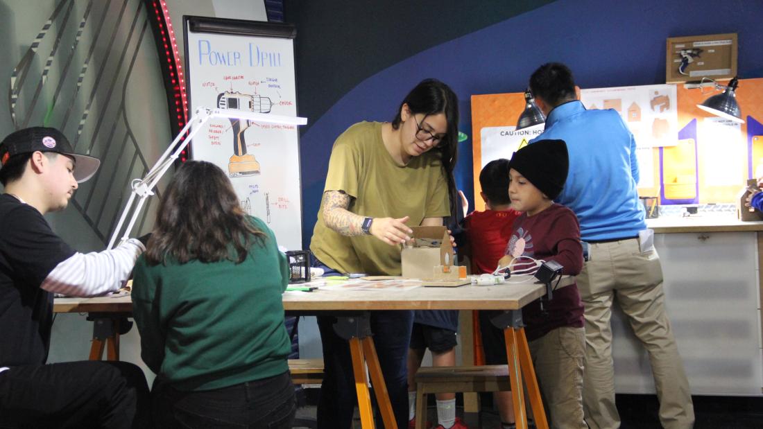 A group of people using a workshop table to build crafts