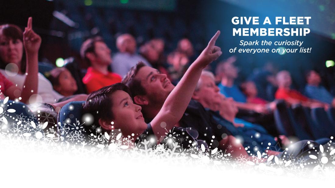 Give the gift of Membership. Spark the curiosity of everyone on your list! With image of a boy and his father sitting in a theater pointing at the screen with excitement in their faces, and graphics of snowflakes in the bottom of the image..  