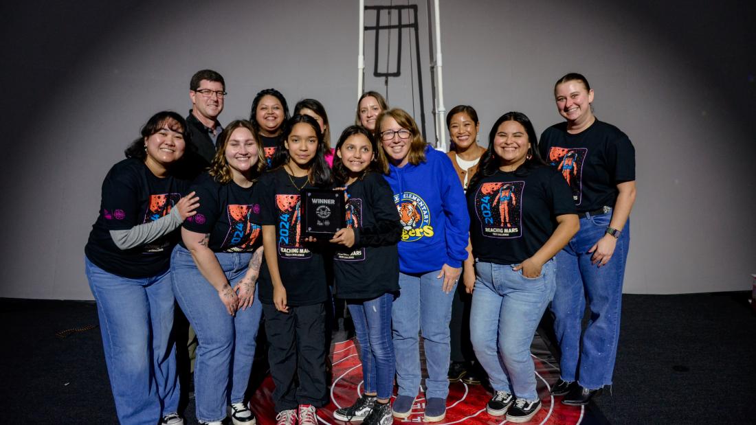 The winning group of SciTech girls standing in the stage of the Heikoff Giant Dome Theater with their science teacher and the Fleet's educators.