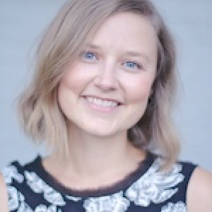 Dr. Jessica Cassin. Blond woman smiling on dark dress with white flower stamped. 