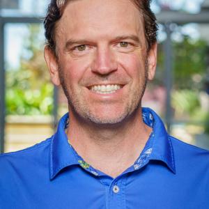 Jon Pokorski. A man smiling with a blue Hawaiian shirt, yellow flowers.