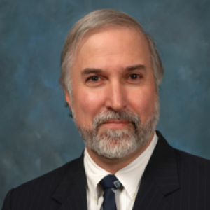 A portrait of a man on a dark suit and white shirt.